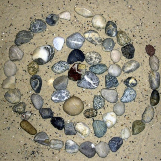 bunte Steine in Form einer Spirale auf Sand